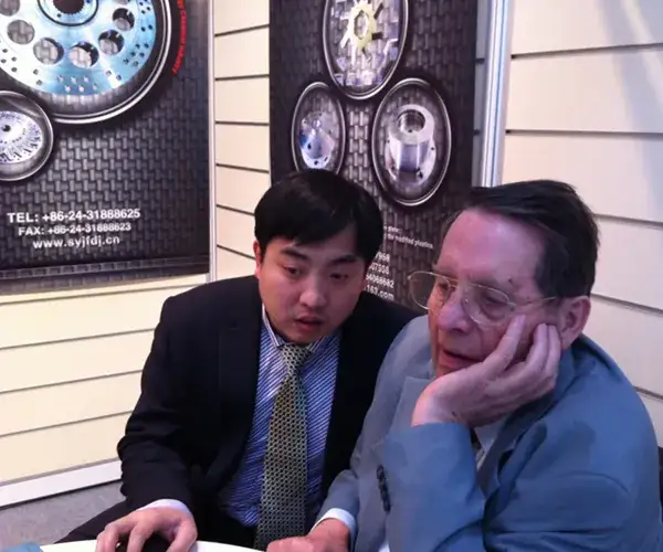 Two men discussing products beside a die plate display