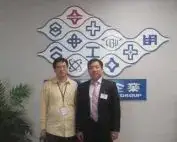 Two men standing in front of a Formosa Plastics Group sign