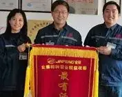 Three employees holding an award banner